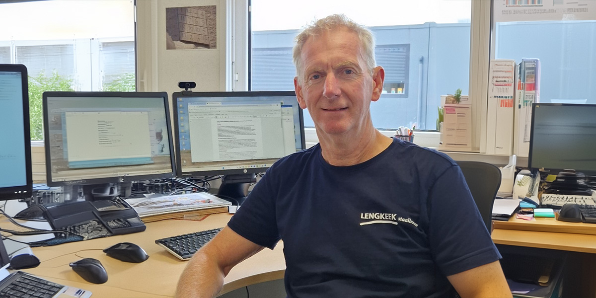 Lengkeek steel colleague sitting at desk and looking at camera